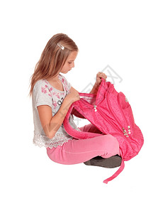 一个美丽的年轻女孩打开她的粉红色背包看着它惊讶她发现什么孤立的白色背景背景图片