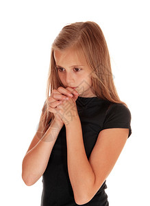 一个穿着黑色毛衣的漂亮女孩双手折叠祈祷为白色背景而孤立无援图片