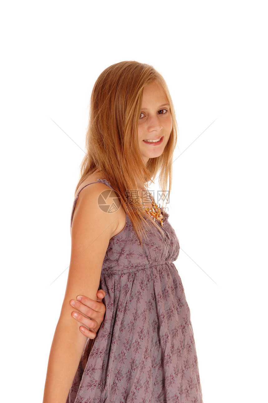 一个美丽的小女孩站在布根迪的裙子上侧面孤立的白色背景和微笑图片