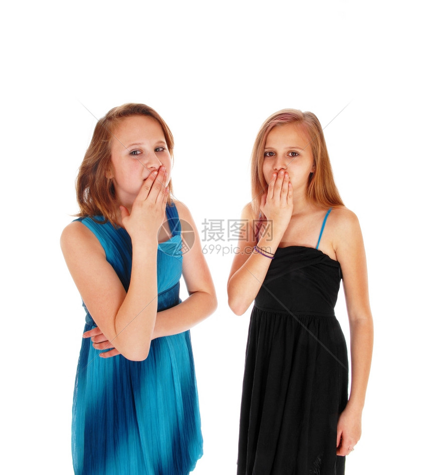 两个穿蓝衣和黑的未成年女孩站在那里手伸到嘴边被白种背景隔离图片