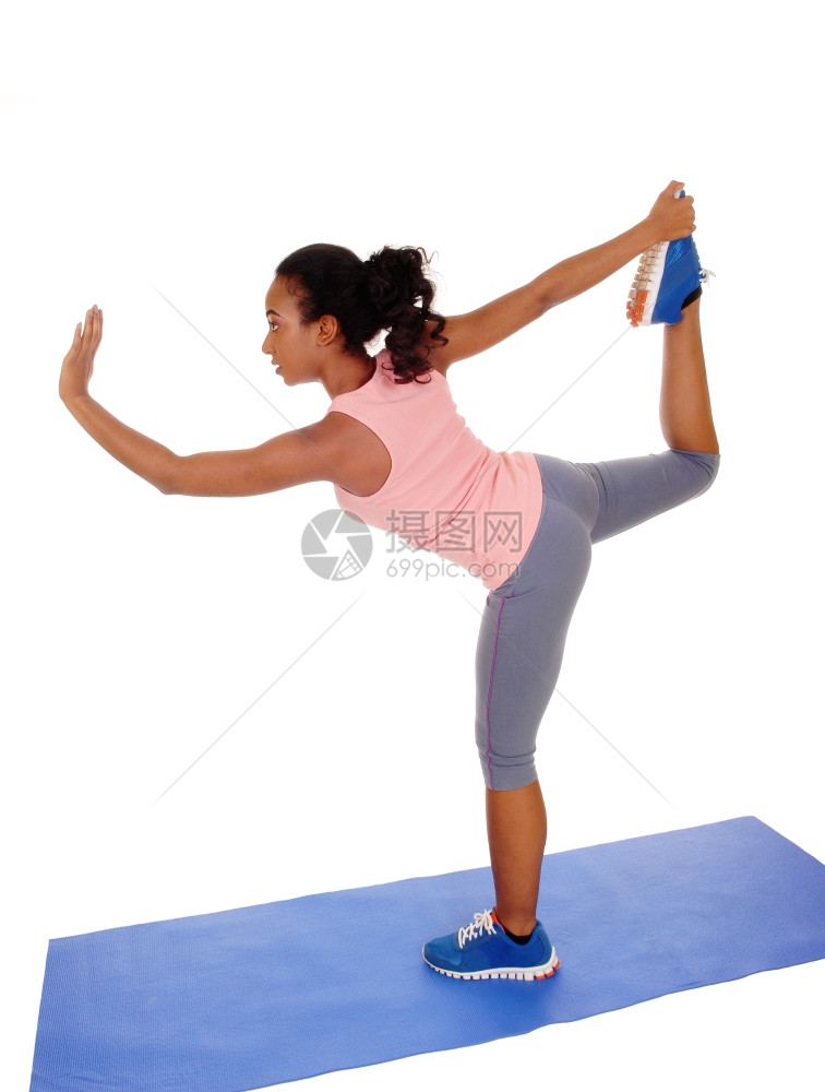 一名非洲裔美国女孩站在瑜伽垫上穿着蓝色紧身裤伸展与白人背景隔绝图片
