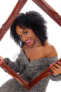 一个美丽笑容的非裔国妇女带着一幅画框和长相的槽子穿着灰色毛衣与白背景隔绝图片