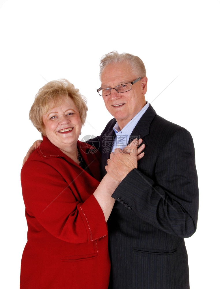 一个快乐的老夫妇站着面对手牵微笑孤立的白背景图片