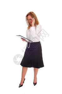 一位身着黑裙子的女商人穿着白衬衫拿她的剪贴板看着与白色背景隔绝图片