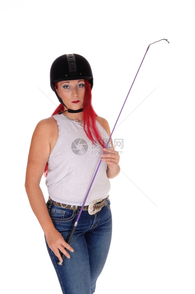 一个快乐的女人带着她骑手头盔和鞭子长的红发孤立白色背景图片