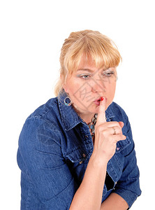 一个漂亮的金发女人肖像穿着牛仔裤夹克将她的指头放在嘴上与白种背景隔绝图片