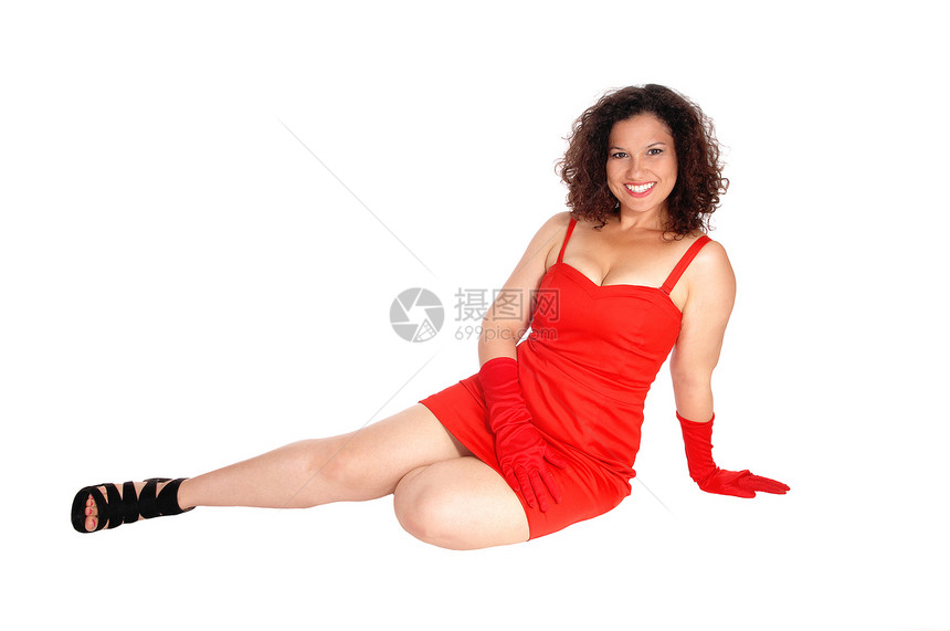 一个穿着红裙子和花纹的年轻美女坐在地板上微笑着与白种背景隔绝图片