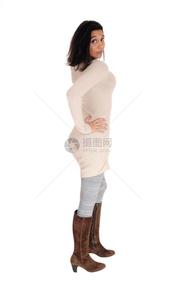 一位西班牙裔年轻女穿着针织裙子棕靴与白种背景隔绝图片