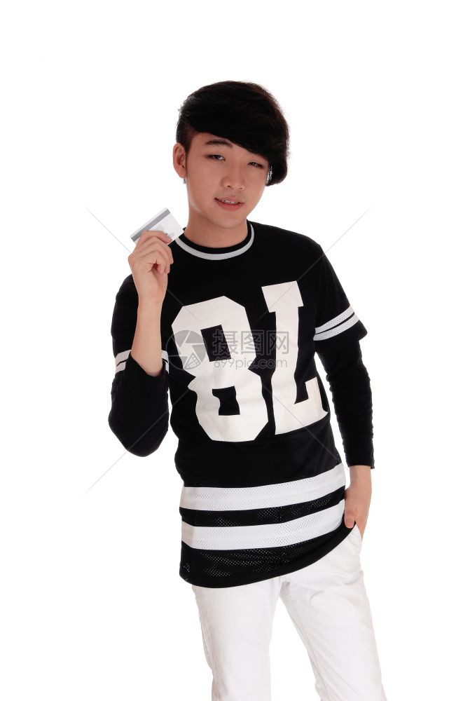 一个英俊的年轻亚洲青少站在黑色T恤持有他的信用卡花钱孤立的白色背景图片