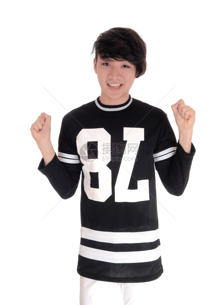 一个英俊的亚洲青少年站在黑色T恤上举起拳头庆祝胜利与白种背景隔绝图片
