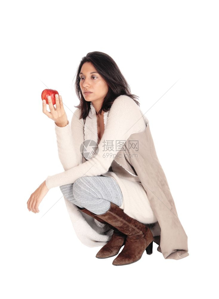 一位美丽的西班牙女人跪在地板上拿着红苹果被白种背景孤立图片