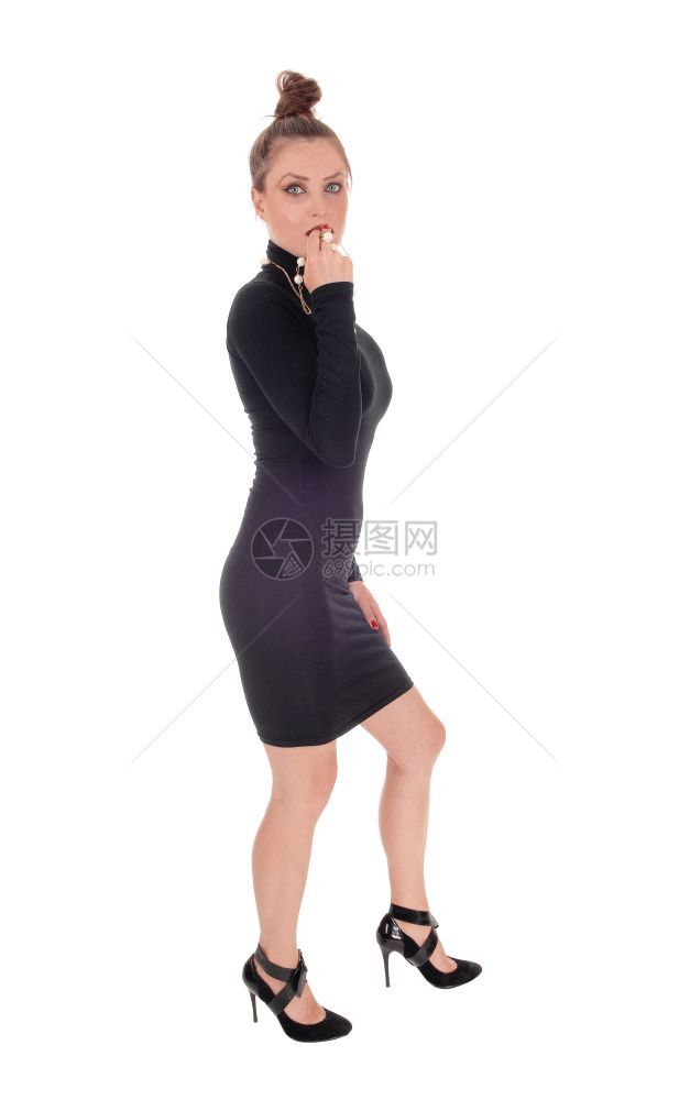 一个美丽的年轻高加索女人穿着黑色裙子高跟鞋看悲伤与白种背景隔绝图片