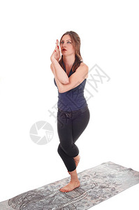 一个穿着运动服的瘦年轻女子站在灰毛巾上一条腿和手臂扭曲图片