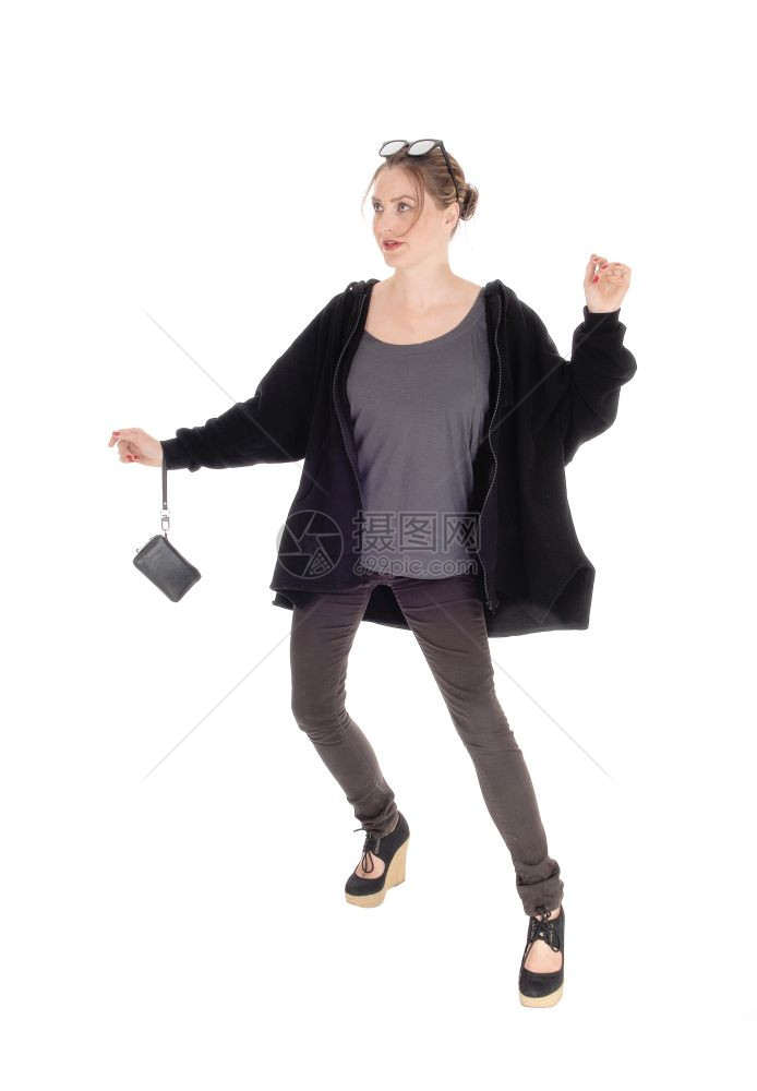 一个穿黑夹克的瘦年轻女人和一个小钱包准备散步头发上戴墨镜被白背景隔离图片