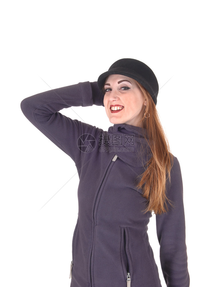一位可爱的年轻女子穿着冬大衣和帽子戴着一只手握头部微笑与白种背景隔绝图片