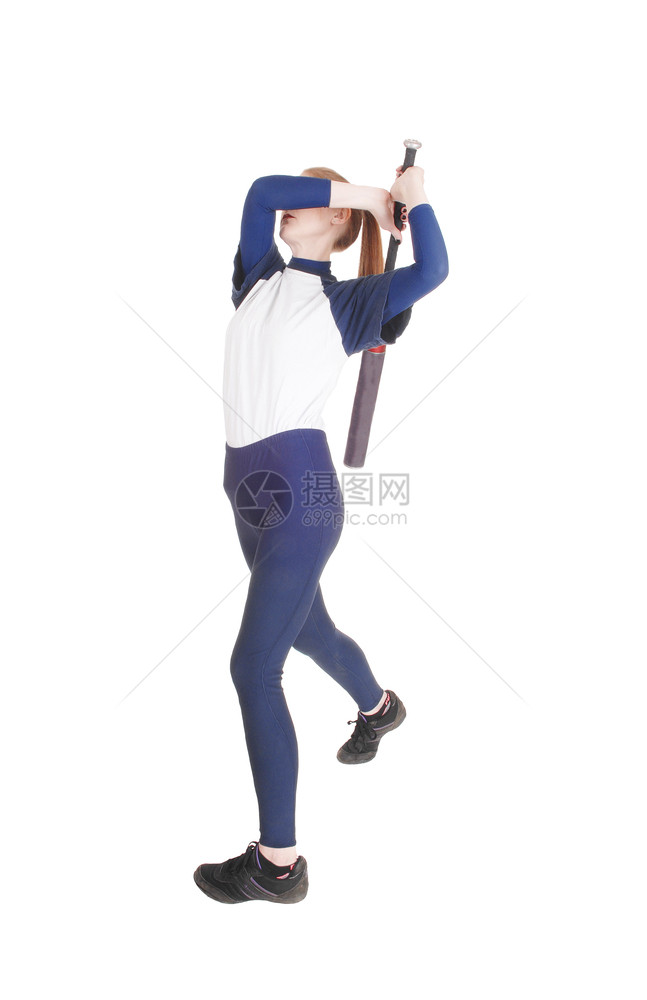 一个打垒球的瘦年轻女人挥着她的坏拳打球穿着蓝色制服与白背景隔绝图片