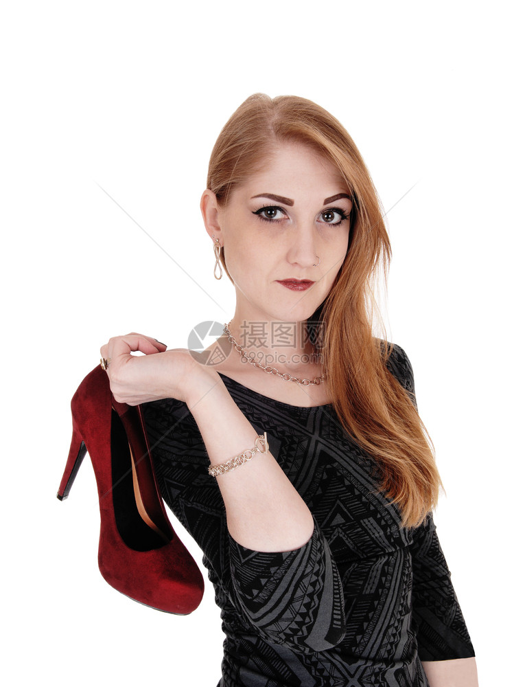 一个女人的特写镜头深色头发穿着服装肩上扛着一只红色高跟鞋与白色背景隔离图片