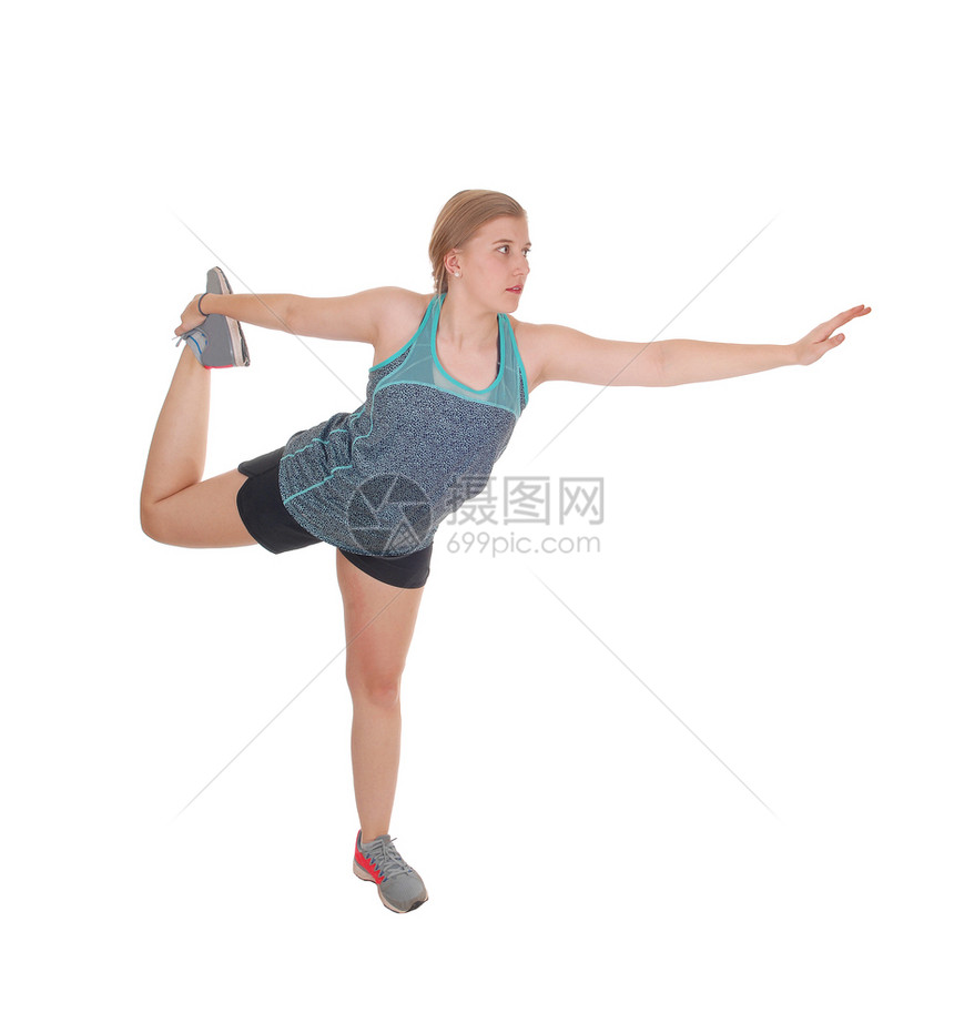 一位年轻美女站在白背景的孤立旁身体用一条腿伸展手臂图片