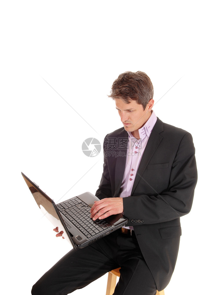 一个严肃的年轻商人穿着西装和笔记本电脑坐在Keyport的这段剪切机上因白色背景被隔离图片