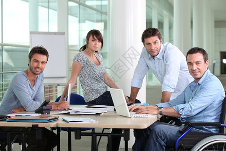 男坐在轮椅上和同事坐在桌子上图片