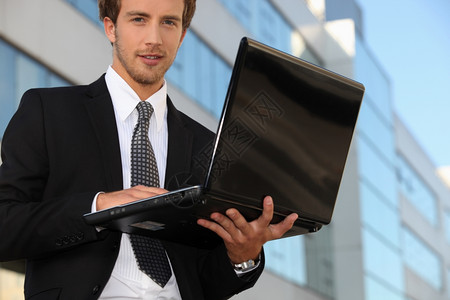 配备膝上型计算机的办公室外青年商务背景图片