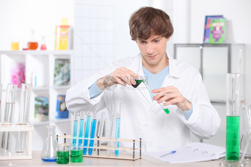 实验室里的年轻科学家正在一个测试管里灌一些化合物图片