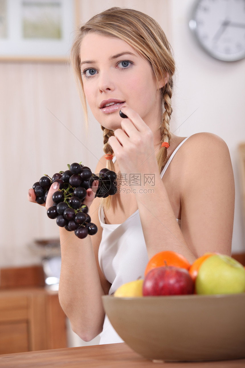 金发美女在厨房吃红葡萄图片