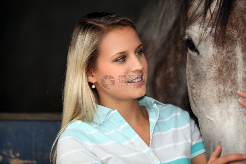 年轻女人爱抚马匹图片