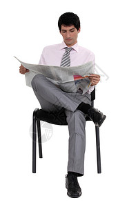 一个商人在椅子上读报纸图片