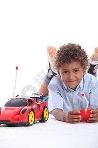 年轻男孩玩红色遥控运动车图片