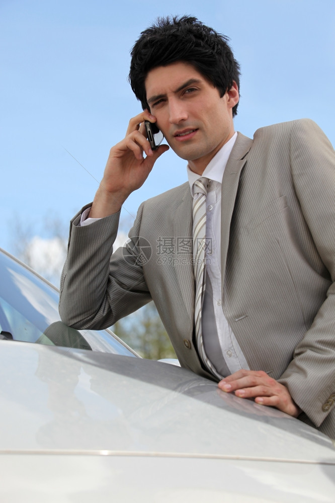 愤怒的商人在汽车旁用手机说话图片