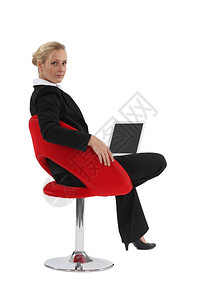 坐在椅子上并使用笔记本电脑的妇女图片