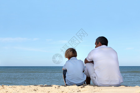 父亲和儿子坐在海洋的边缘图片