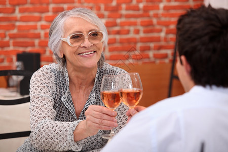 年长妇女在一家餐馆和个年轻男子起喝玫瑰酒图片