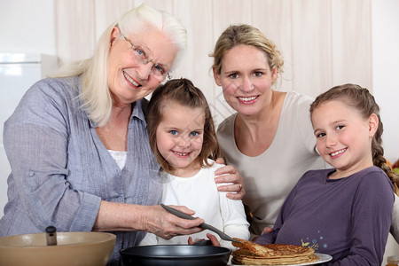 外祖母在女儿和孙的周围做煎饼图片