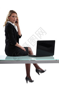 坐在办公桌上的商业妇女图片