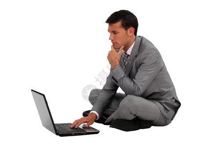 坐在手持笔记本电脑交叉腿的商人图片