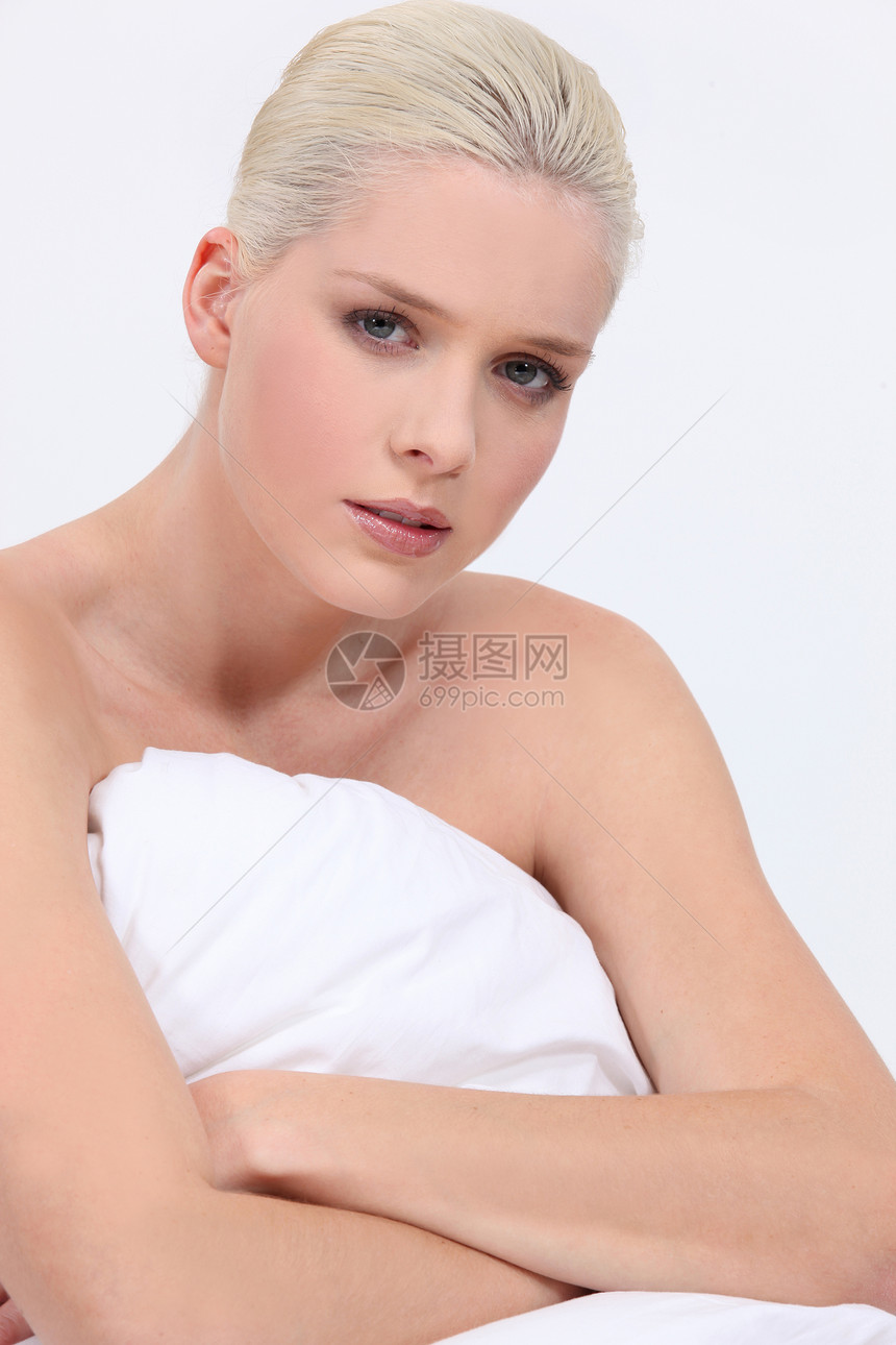赤裸的金发妇女坐在床上面部表情中立图片