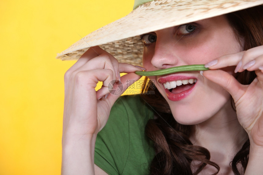 玩耍的女人拿着绿色豆子在她的上唇方图片