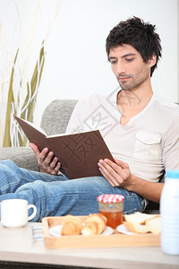 男人在吃早餐时看书图片