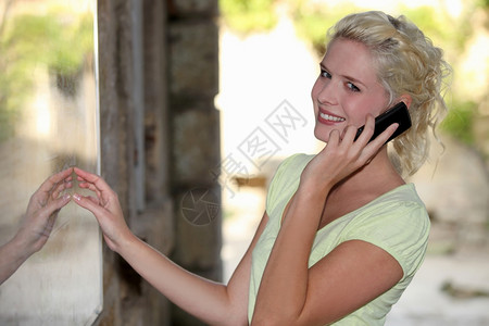 以移动电话在餐馆外用手机的Blond妇女图片