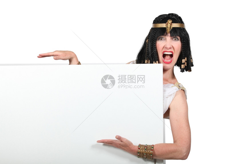 身着Cleopatra服装的妇女指着一个空白的标志图片
