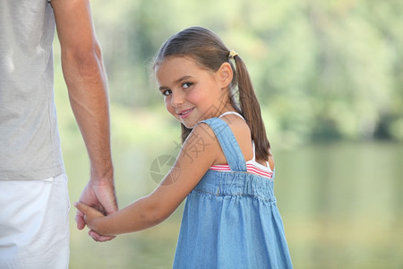 年轻女孩与父母一起在湖边散步图片