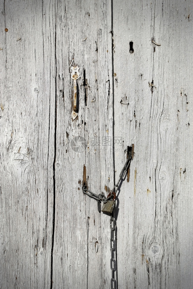 铁链上挂有把手和锁链的非常老旧木门图片