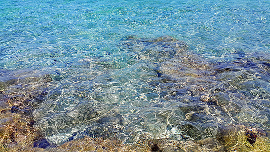 靠近岩石海岸的透明水背景图片