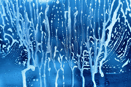 玻璃上含肥皂泡沫的亮蓝抽象纹理图片