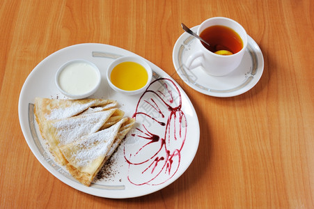 煎饼标志茶和煎饼加奶粉糖菜盘由牛莓果酱装饰背景