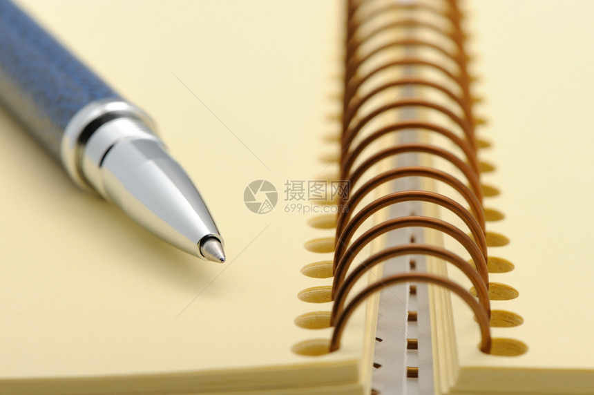 笔和记本在黄纸的螺旋上图片