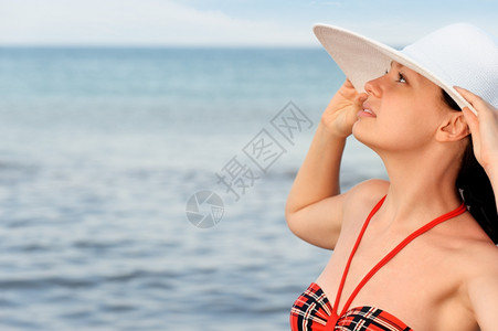那个戴着帽子的女孩顶着大海和蓝天空图片