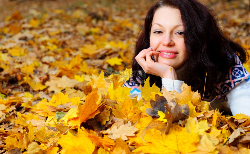 秋天森林中迷人的女躺在黄叶上图片